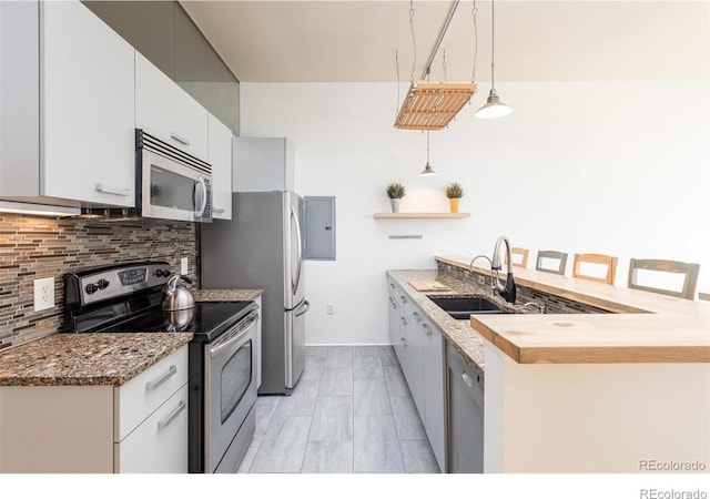3100 Huron St Unit 3P, Denver, CO 80202 - kitchen with appliances with stainless steel finishes, decorative backsplash, a peninsula, electric panel, and open shelves