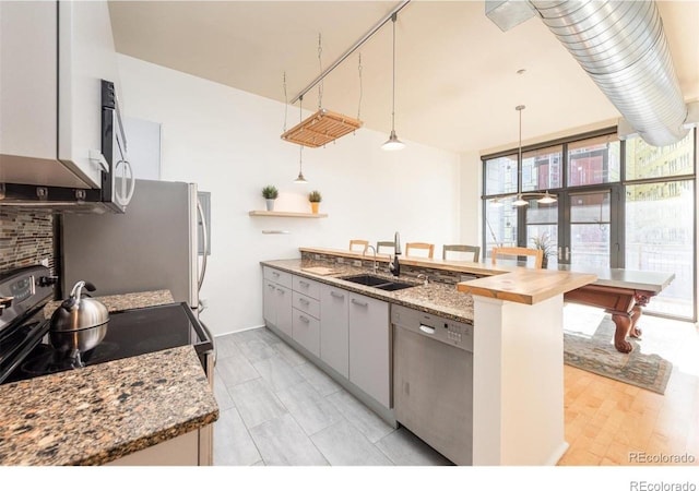 3100 Huron St Unit 3P, Denver, CO 80202 - kitchen featuring appliances with stainless steel finishes, a peninsula, hanging light fixtures, wood counters, and gray cabinetry