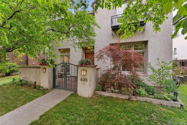 view of front of property featuring stucco siding, fence private yard, a gate, and a front lawn
