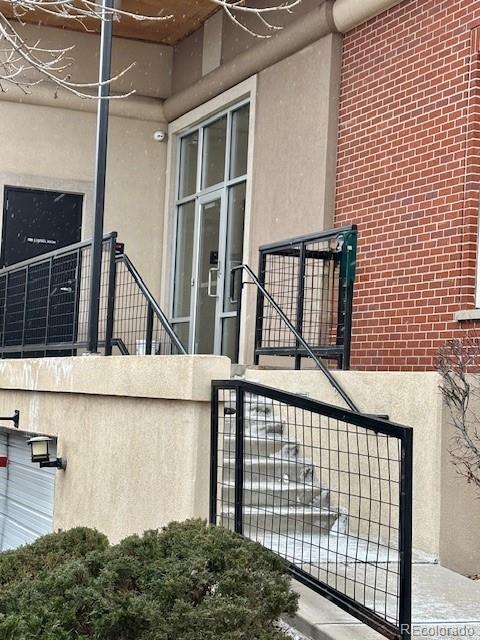 entrance to property with brick siding, fence, and stucco siding