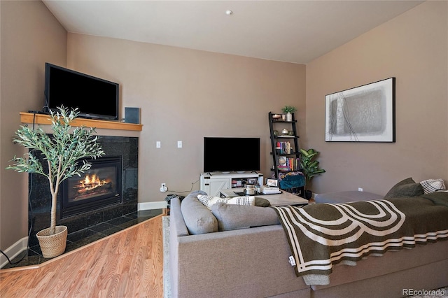 living area with a fireplace, wood finished floors, and baseboards