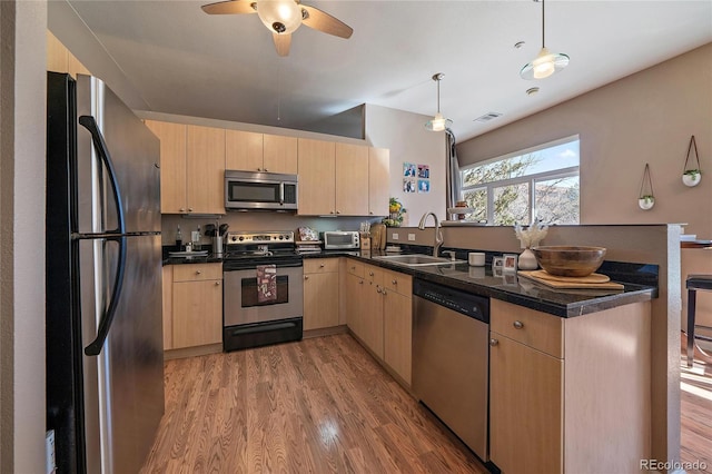 kitchen with a sink, appliances with stainless steel finishes, light brown cabinets, and light wood-style flooring