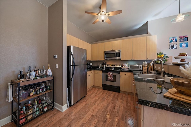 kitchen with wood finished floors, a sink, a ceiling fan, appliances with stainless steel finishes, and light brown cabinetry