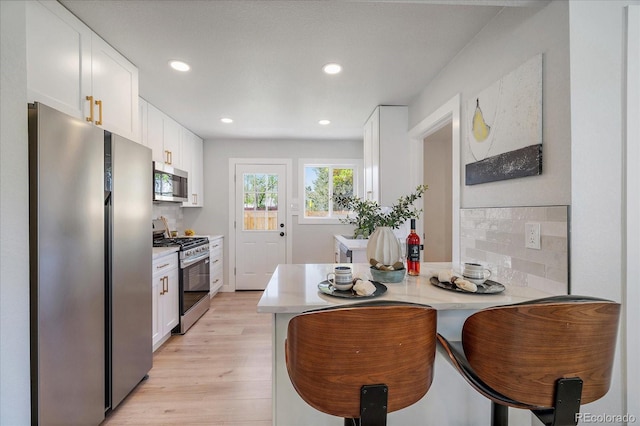 3206 Elizabeth St, Denver, CO 80205 - kitchen featuring appliances with stainless steel finishes, light countertops, white cabinets, a peninsula, and recessed lighting