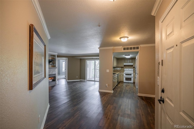 12208 W Dorado Pl Unit 207, Littleton, CO 80127 - entrance foyer featuring crown molding, dark wood-style floors, a warm lit fireplace, and a textured ceiling