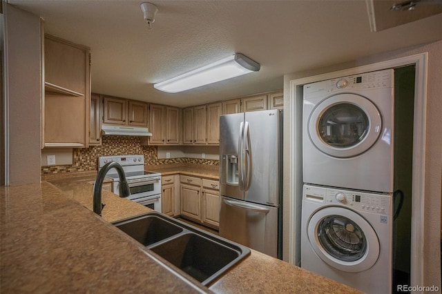 12208 W Dorado Pl Unit 207, Littleton, CO 80127 - kitchen featuring stainless steel fridge, range with two ovens, stacked washer / drying machine, under cabinet range hood, and backsplash