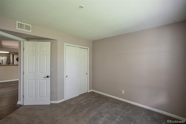 12208 W Dorado Pl Unit 207, Littleton, CO 80127 - unfurnished bedroom with freestanding refrigerator, a closet, dark colored carpet, and washer / dryer