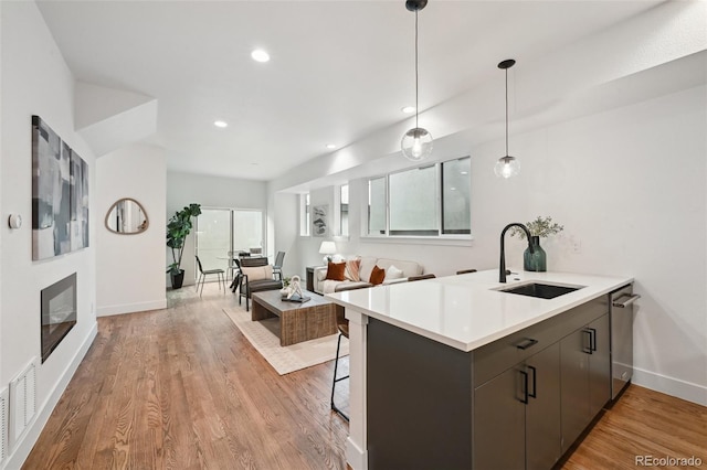 kitchen featuring sink, a breakfast bar area, kitchen peninsula, dark brown cabinets, and light hardwood / wood-style flooring