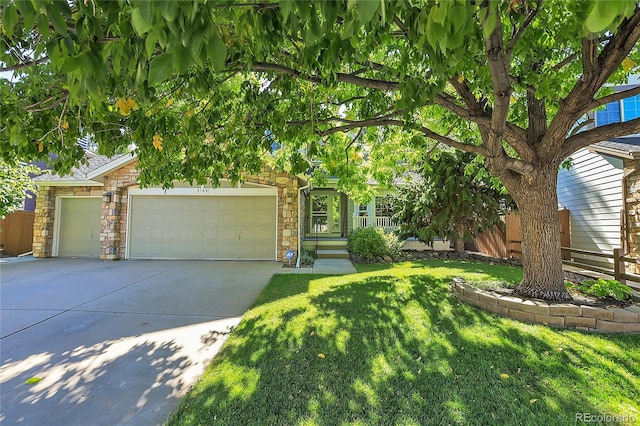 view of property hidden behind natural elements featuring a front lawn and a garage