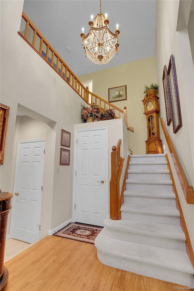 entryway with light wood-type flooring, a towering ceiling, and an inviting chandelier