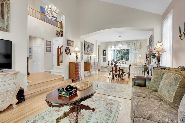 living room featuring a notable chandelier, wood-type flooring, and high vaulted ceiling