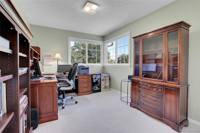 carpeted office featuring a textured ceiling