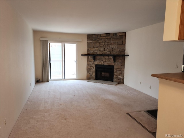 unfurnished living room with a stone fireplace and carpet