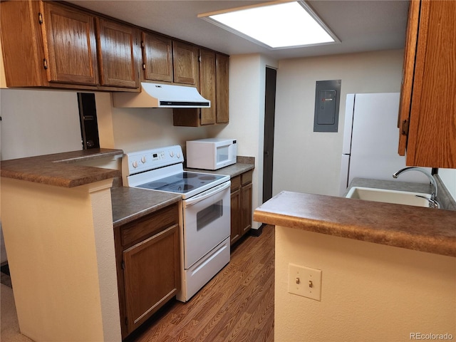 kitchen with dark countertops, a sink, white appliances, electric panel, and under cabinet range hood