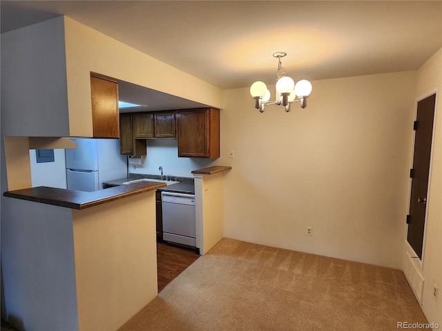 kitchen with white appliances, dark countertops, decorative light fixtures, a peninsula, and a notable chandelier