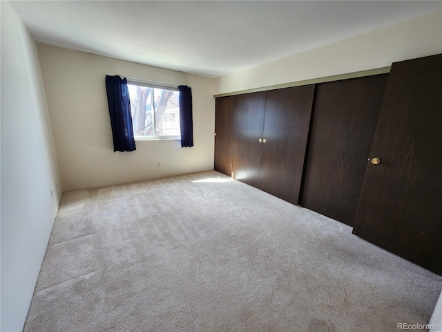 unfurnished bedroom featuring a closet and light colored carpet