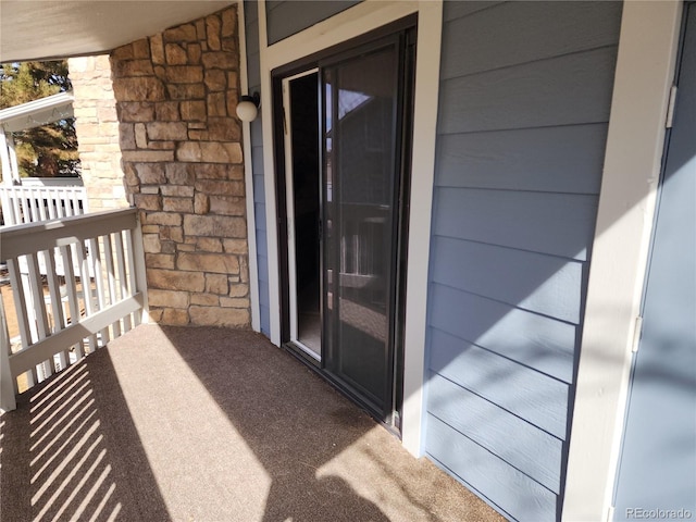 entrance to property with stone siding and a balcony