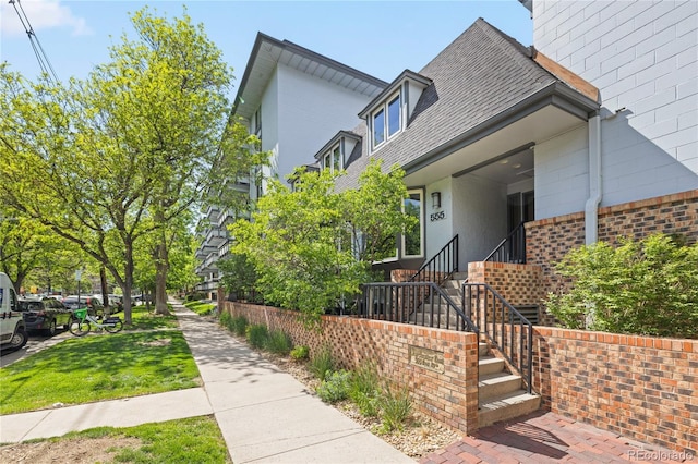 555 E 10th Ave Unit 111, Denver, CO 80203 - view of property exterior with brick siding and roof with shingles