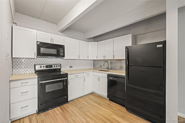 555 E 10th Ave Unit 111, Denver, CO 80203 - kitchen featuring black appliances, a sink, beamed ceiling, light countertops, and white cabinetry