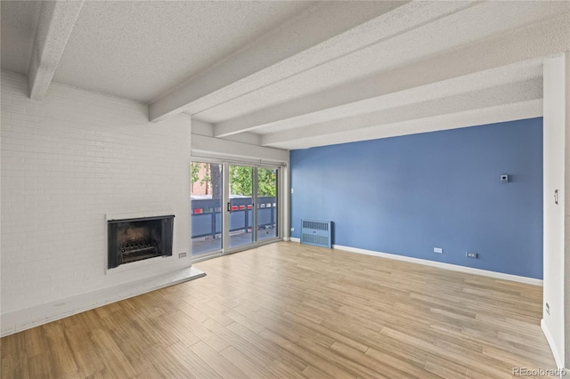 555 E 10th Ave Unit 111, Denver, CO 80203 - unfurnished living room featuring baseboards, a textured ceiling, a fireplace, beamed ceiling, and wood finished floors
