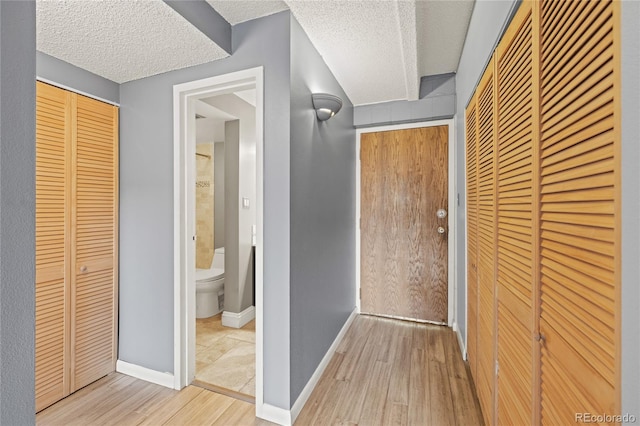 555 E 10th Ave Unit 111, Denver, CO 80203 - hallway featuring wood finished floors, a textured ceiling, and baseboards