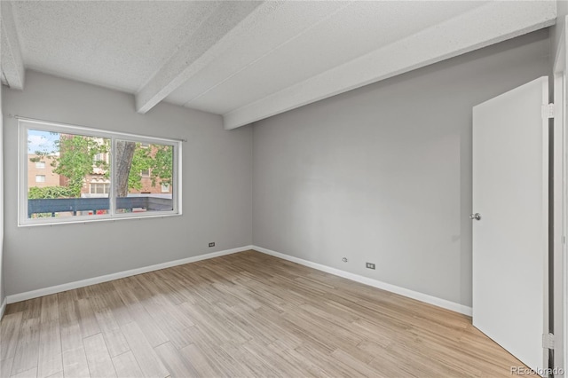 555 E 10th Ave Unit 111, Denver, CO 80203 - empty room with beamed ceiling, light wood-type flooring, a textured ceiling, and baseboards