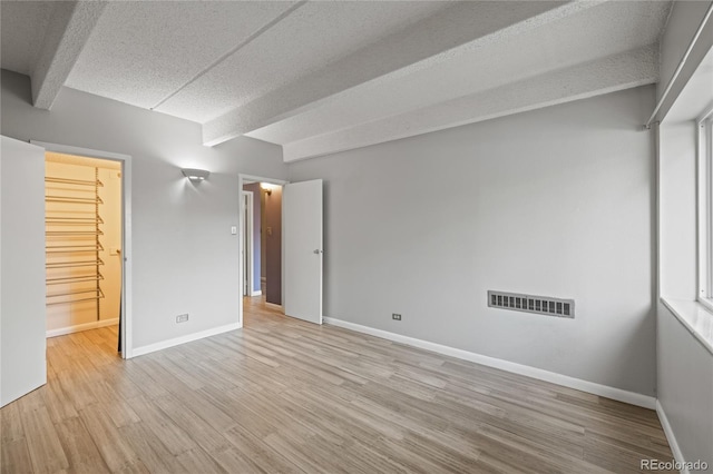 555 E 10th Ave Unit 111, Denver, CO 80203 - unfurnished room featuring baseboards, wood finished floors, a textured ceiling, and beamed ceiling