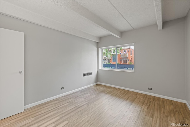 555 E 10th Ave Unit 111, Denver, CO 80203 - unfurnished room featuring wood finished floors, beamed ceiling, a textured ceiling, and baseboards