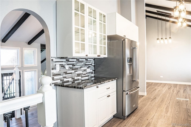 kitchen with hanging light fixtures, tasteful backsplash, dark stone counters, light hardwood / wood-style floors, and white cabinets