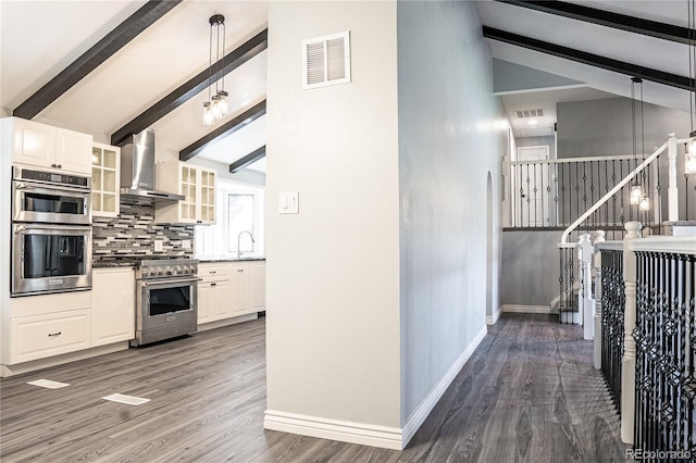 kitchen featuring hanging light fixtures, stainless steel appliances, wall chimney range hood, lofted ceiling with beams, and dark hardwood / wood-style floors