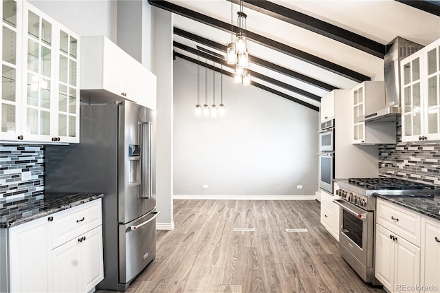 kitchen featuring premium appliances, vaulted ceiling with beams, backsplash, dark stone countertops, and light wood-type flooring