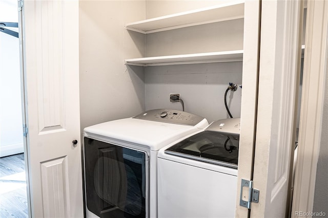 clothes washing area with separate washer and dryer and hardwood / wood-style flooring