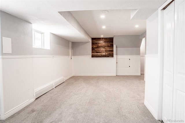 basement featuring a textured ceiling, wood walls, light carpet, and a baseboard heating unit