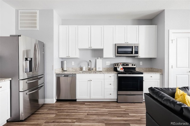 kitchen featuring appliances with stainless steel finishes, sink, wood-type flooring, and white cabinets