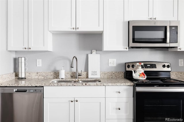 kitchen with light stone countertops, white cabinetry, appliances with stainless steel finishes, and sink