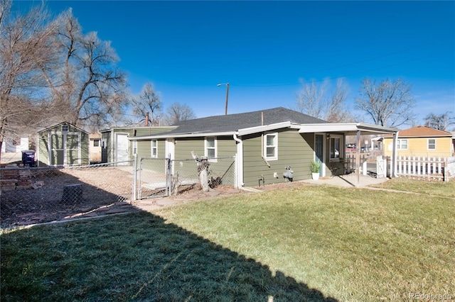 back of house featuring fence, a lawn, a patio area, an outbuilding, and a gate