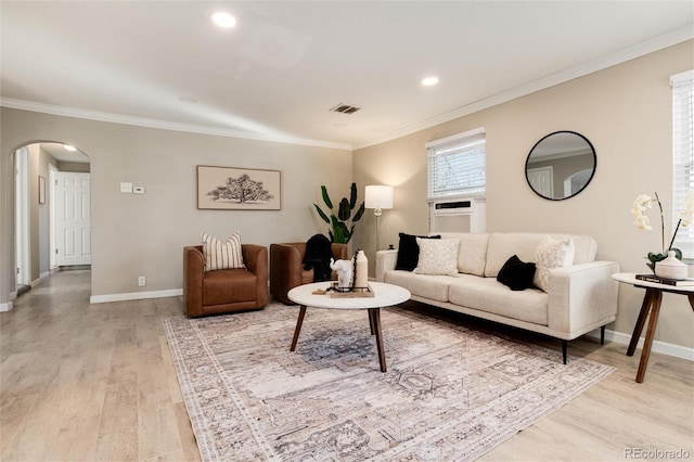 living area featuring baseboards, light wood finished floors, recessed lighting, arched walkways, and ornamental molding