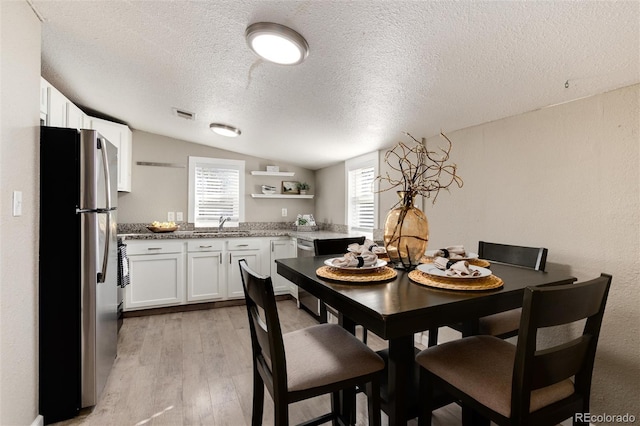 dining space featuring visible vents, lofted ceiling, plenty of natural light, and light wood-style flooring