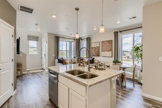 kitchen featuring sink, a center island with sink, dishwasher, white cabinets, and hanging light fixtures