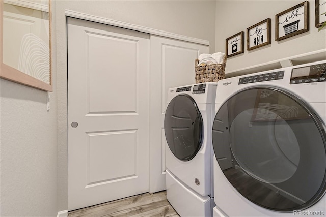 clothes washing area featuring washer and clothes dryer and light hardwood / wood-style floors