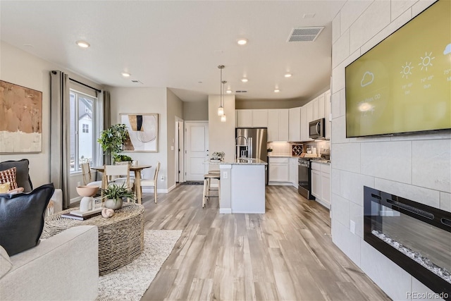 living room featuring a tiled fireplace and light wood-type flooring