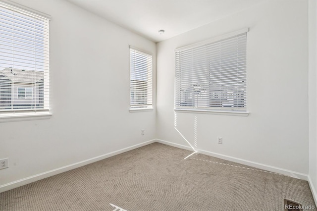 carpeted empty room featuring baseboards