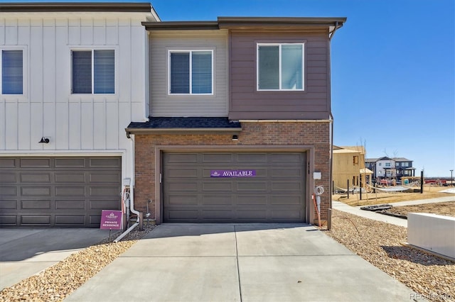 multi unit property featuring an attached garage, board and batten siding, concrete driveway, and brick siding