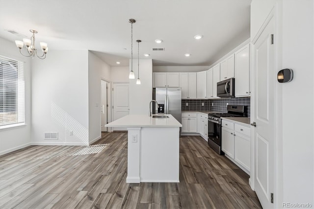 kitchen featuring appliances with stainless steel finishes, wood finished floors, visible vents, and tasteful backsplash