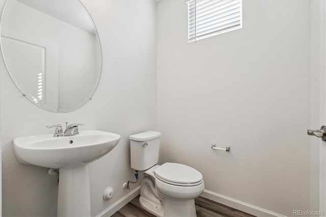 bathroom with toilet, baseboards, and wood finished floors