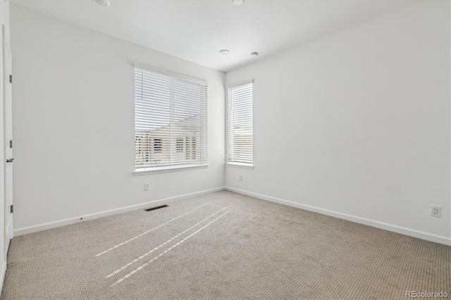 spare room featuring baseboards, visible vents, and carpet flooring