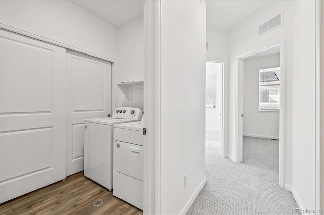 washroom featuring light colored carpet, laundry area, separate washer and dryer, visible vents, and baseboards