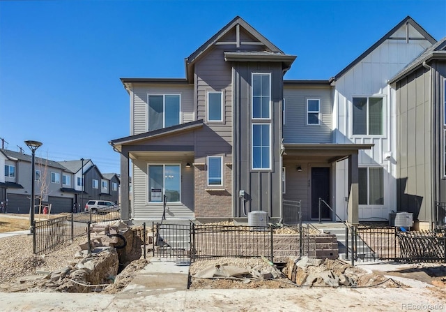 view of front of home featuring board and batten siding, a residential view, and fence