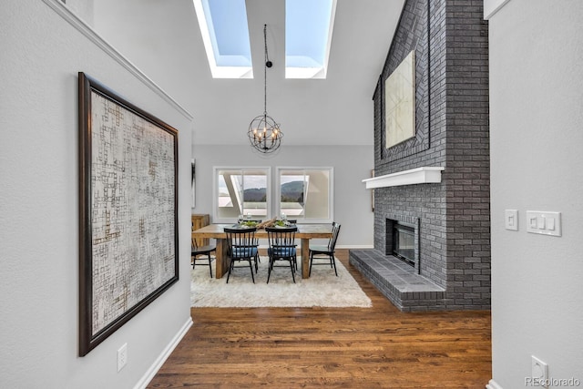 dining space with lofted ceiling with skylight, dark hardwood / wood-style floors, an inviting chandelier, and a fireplace