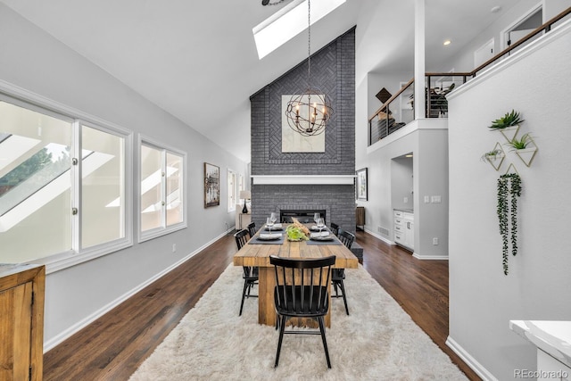 dining space with an inviting chandelier, a fireplace, a skylight, and dark wood-type flooring